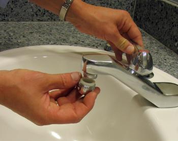 Two hands installing a faucet aerator. 